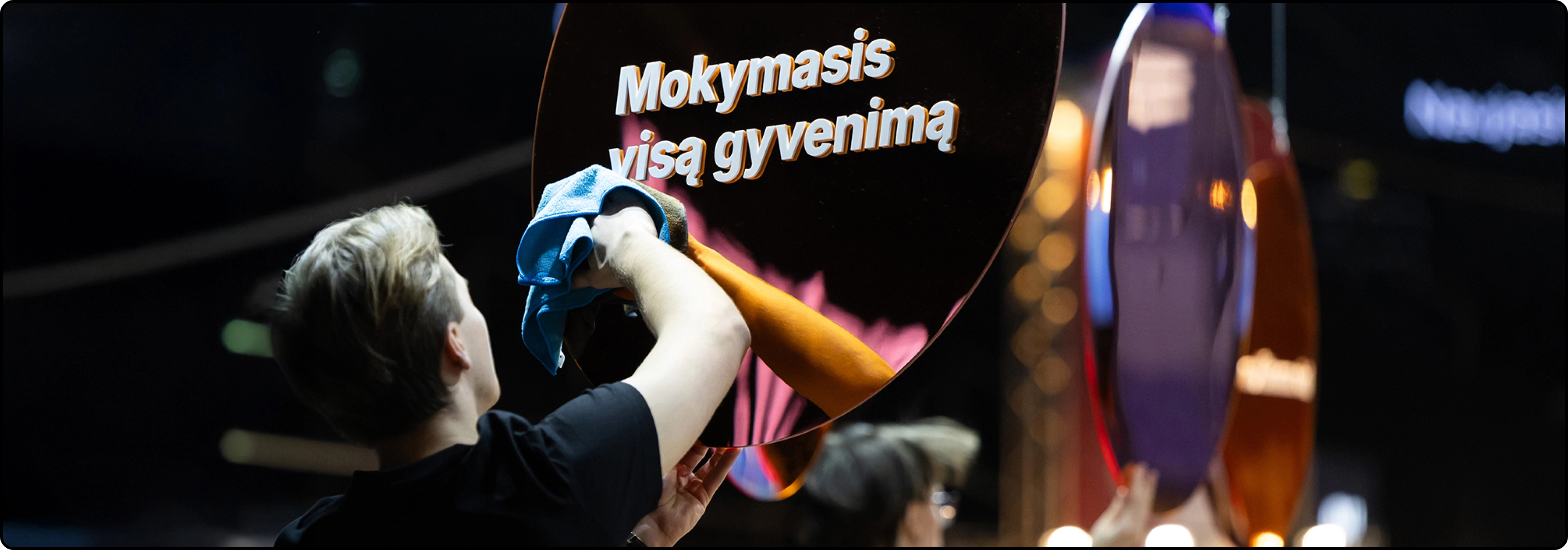 KTU Mokymosi visą gyvenimą puslapio „Kodėl mes“ baneris – žmogus valo blizgantį apvalų paviršių su užrašu „Mokymasis visą gyvenimą“.